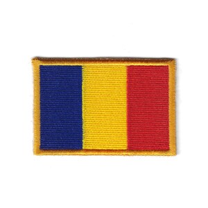 May include: Embroidered patch featuring the flag of Romania. The rectangular patch has vertical stripes in blue, yellow, and red, with a gold border. The patch is likely for clothing or accessories.