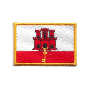 Könnte beinhalten: Gestickter Aufnäher mit der Flagge von Gibraltar. Das Design zeigt ein rotes Schloss, einen goldenen Schlüssel und einen weißen und roten Hintergrund, alles umrahmt von einem goldenen Rand. Geeignet für Jacken, Taschen oder andere Textilien.