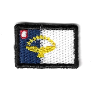 May include: An embroidered patch featuring the flag of the Northern Mariana Islands. The flag is blue and white with a yellow symbol in the center.