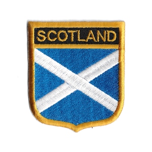 May include: A blue and white embroidered patch with a gold border and the word "SCOTLAND" in black lettering.