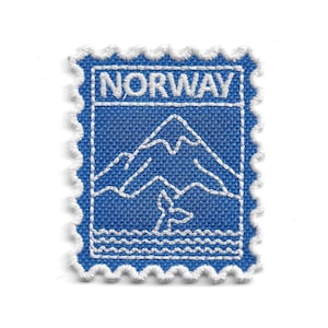 Peut inclure: Un écusson brodé rectangulaire avec une bordure blanche festonnée, sur fond bleu avec des motifs cousus en blanc. Le design représente une chaîne de montagnes au-dessus de l'eau avec une queue de baleine, et le texte NORWAY est brodé en haut.