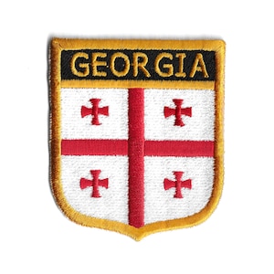 May include: An embroidered patch with a gold border and the word "GEORGIA" in black lettering. The patch features the Georgian flag, which is a white field with a red cross and four smaller red crosses in the corners.