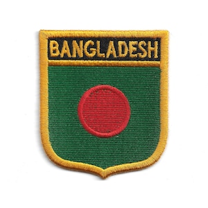 以下が含まれることがあります： 金色の「BANGLADESH」の文字が刺繍されたパッチ。緑色のフィールドに赤い円が配置されています。パッチは金色の縁取りと盾の形をしています。