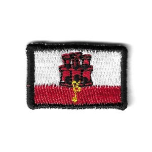 May include: A red, white, and gold embroidered patch featuring the flag of Gibraltar. The flag depicts a red castle with a gold key.