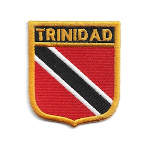 May include: Embroidered patch featuring the word "TRINIDAD" in gold lettering above a red shield. The shield has a black diagonal stripe with a white border, and a gold border.