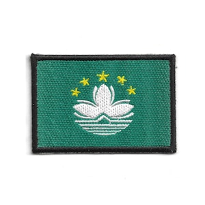May include: A rectangular patch featuring the flag of Macau. The patch has a green background with a white lotus flower and five yellow stars. The border is black.