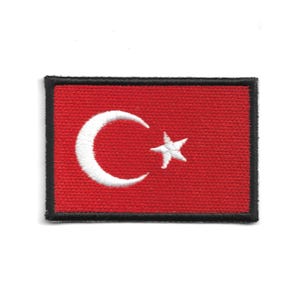 May include: Embroidered patch featuring the Turkish flag. The design includes a red background with a white crescent moon and star, framed by a black border. The patch is rectangular.