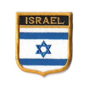 May include: An embroidered patch featuring the Israeli flag. The patch is shaped like a shield with a gold border and a black background with the word "ISRAEL" in gold lettering. The flag is white with two blue stripes and a blue Star of David in the centre.