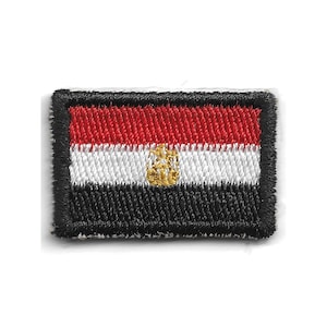 Op de afbeelding: Een rechthoekige geborduurde patch met de nationale vlag van Egypte. Het ontwerp bestaat uit drie horizontale banen in rood, wit en zwart, met een goudkleurig adelaarsembleem in het midden van de witte baan en een dikke zwarte rand.