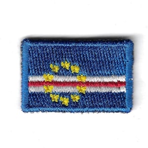 May include: A blue embroidered patch featuring the flag of Cape Verde. The flag design includes a circle of yellow stars in the centre, a red stripe, and a white stripe.