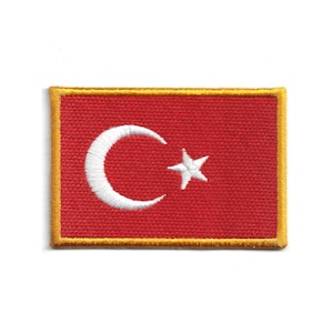 May include: Embroidered patch featuring the Turkish flag. The patch has a red background with a white crescent moon and star. The border is gold. The patch is rectangular in shape.