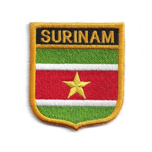 May include: Embroidered patch featuring the word "SURINAM" in black on a gold background. The patch displays the flag of Suriname, with green and white stripes above and below a red central band with a yellow star.