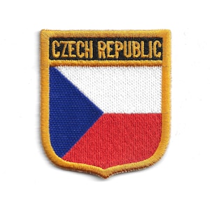 Puede incluir: Parche bordado con la bandera de la República Checa en forma de escudo. El parche tiene un borde dorado y las palabras "CZECH REPUBLIC" en negro en la parte superior. El diseño de la bandera incluye azul, blanco y rojo.