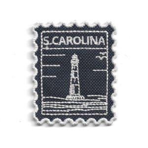 May include: Embroidered patch in the shape of a postage stamp. The patch features a white lighthouse on a dark blue background, with the text "S. CAROLINA" at the top. The edges are scalloped with white thread.