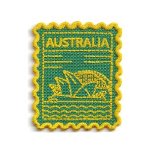 Könnte beinhalten: Ein rechteckiger gestickter Aufnäher mit einem gewellten gelben Rand auf grünem Stoffhintergrund. Das Design zeigt das Wort AUSTRALIA in gelbem Garn oben sowie eine gelb gestickte Umrisslinie des Sydney Opera House über Wellen.