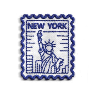 Peut inclure: Écusson brodé représentant la Statue de la Liberté en bleu et le texte "NEW YORK" sur fond blanc. Le patch a une bordure bleue festonnée, ressemblant à un timbre-poste.