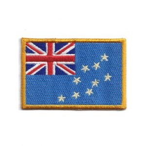 May include: Embroidered patch depicting the flag of the Cook Islands. The design features the Union Jack in the top left, a blue field, and a constellation of 15 white stars. The patch is edged with a gold border.