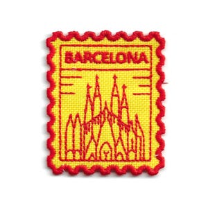 Può includere: Una toppa ricamata gialla con un bordo rosso smerlato. La toppa presenta un'illustrazione rossa di una cattedrale e la scritta "BARCELONA" in lettere rosse.