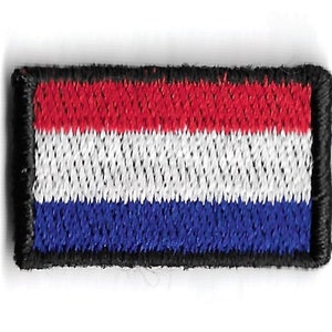 Könnte beinhalten: Ein kleiner gestickter Aufnäher mit der niederländischen Flagge. Die Flagge ist rot, weiß und blau mit einem schwarzen Rand.