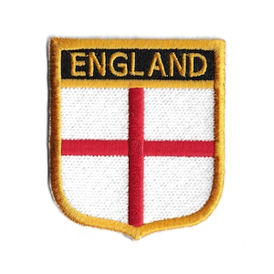 Op de afbeelding: Een gouden geborduurde patch met het woord "ENGLAND" in zwarte letters en een rood kruis op een witte achtergrond.