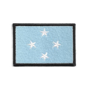May include: Rectangular patch featuring the flag of the Federated States of Micronesia. The patch has a light blue background with four white stars and a black border. The stars are arranged in a diamond pattern.