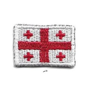 May include: Embroidered patch featuring the flag of Georgia. The flag has a white background with a large red cross dividing the flag into four sections, each with a smaller red cross. The patch has a silver border.