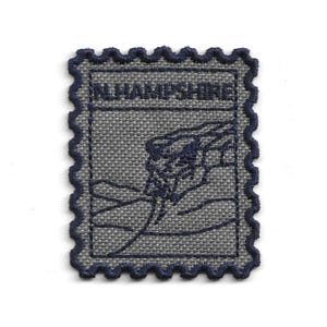 Peut inclure: Un écusson en tissu gris avec une bordure festonnée bleu foncé. Le patch comporte le texte "N. HAMPSHIRE" et un motif brodé bleu foncé d'une montagne et d'une rivière. Le patch est rectangulaire avec un design de timbre-poste.