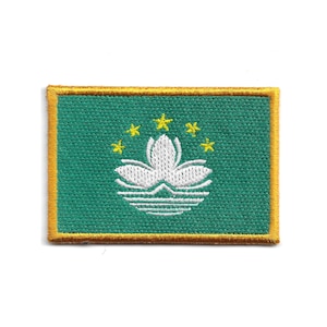 May include: A rectangular patch featuring the flag of Macau. The patch has a green background with a white lotus flower and five yellow stars. The border is gold.