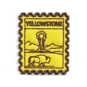 May include: Yellow embroidered patch with a brown scalloped border. The patch features the word "YELLOWSTONE", a tree, mountains, and a bison. The background is yellow.