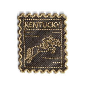 Op de afbeelding: Geborduurde patch in de vorm van een postzegel. De patch is donkerbruin met goudkleurige stiksels. Het woord "KENTUCKY" is bovenaan geborduurd. Een bloemenontwerp staat in het midden. De patch heeft een geschulpte rand.