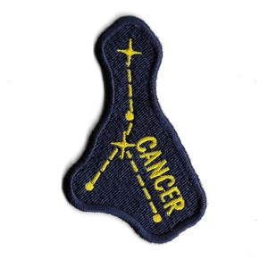 Può includere: Una toppa ricamata blu navy con un contorno giallo della costellazione del Cancro e la parola "CANCRO" scritta verticalmente.