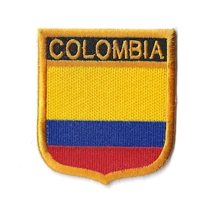 Könnte beinhalten: Ein gestickter Aufnäher in Gelb, Blau und Rot mit dem Wort "COLOMBIA" in schwarzen Buchstaben auf goldenem Hintergrund.