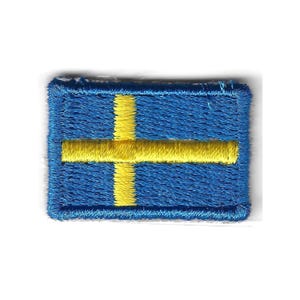 May include: A rectangular embroidered patch featuring the flag of Sweden. The design consists of a blue background with a yellow horizontal stripe and a yellow vertical stripe that intersect to form a cross pattern, finished with a stitched border.