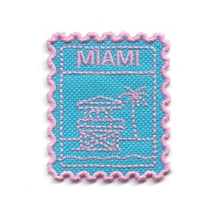 May include: Embroidered patch with a turquoise background and a pink scalloped edge. The patch features the word "MIAMI" in pink, alongside a lifeguard tower and palm tree design, also in pink. The patch is square-shaped.