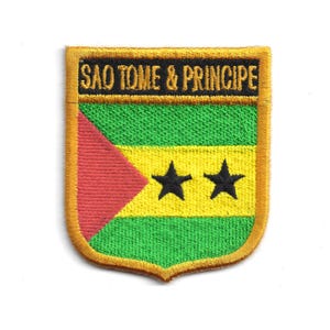 May include: Embroidered patch featuring the flag of São Tomé and Príncipe. The shield-shaped patch has a gold border and displays the flag's colors: green, yellow, red, and black stars. The text "SAO TOME & PRINCIPE" is embroidered across the top.