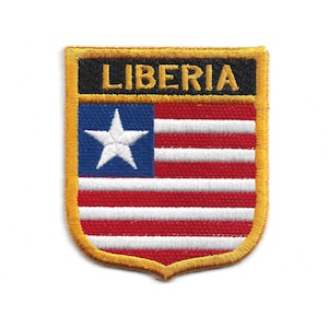 Può includere: Toppa ricamata raffigurante la bandiera della Liberia. La toppa ha un bordo dorato e una forma a scudo. La sezione superiore presenta la scritta "LIBERIA" in lettere dorate su sfondo nero. Il disegno della bandiera include un quadrato blu con una stella bianca e strisce rosse e bianche.