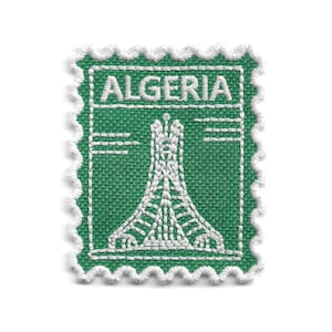 May include: A rectangular embroidered patch with a scalloped white border, featuring a green background and white stitching. The word ALGERIA is embroidered at the top, and a white stylized depiction of the Maqam Echahid monument is centered below.