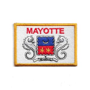 Peut inclure: Écusson brodé avec le mot "MAYOTTE" en rouge. Il présente des hippocampes et un écusson bleu et rouge sur fond blanc, avec une bordure dorée.