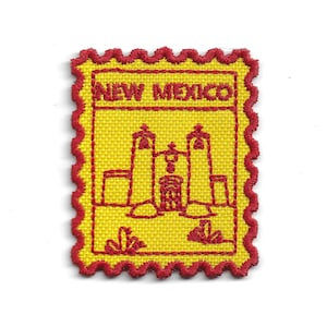 Może przedstawiać: Żółta haftowana naszywka z czerwonym, falistym obramowaniem. Naszywka przedstawia czerwony kontur budynku i napis "NEW MEXICO" w kolorze czerwonym. Naszywka ma kształt prostokąta.