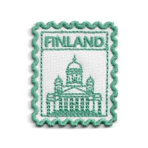 May include: A rectangular embroidered patch with a scalloped edge in teal thread on a white fabric base. The design features the word FINLAND in teal capital letters above a teal embroidered outline of a cathedral with a central dome.