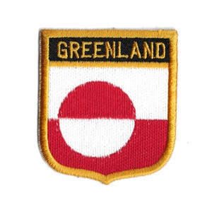 Puede incluir: Un parche bordado en oro con la palabra "GREENLAND" en letras negras sobre fondo negro. El parche presenta la bandera de Groenlandia, que es un fondo rojo con un círculo blanco en el centro.
