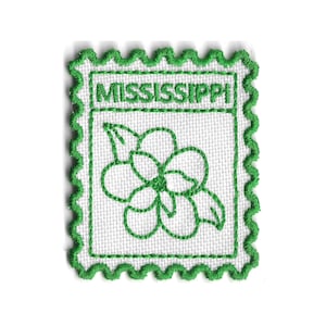 Può includere: Una toppa quadrata bianca con un contorno ricamato verde e bordi smerlati. La toppa presenta un disegno floreale verde e la parola "MISSISSIPPI" in lettere verdi.