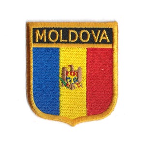 Könnte beinhalten: Gestickter Aufnäher mit der Flagge Moldawiens. Der schildförmige Aufnäher hat einen goldenen Rand und das Wort "MOLDOVA" oben. Das Flaggen-Design umfasst blaue, gelbe und rote vertikale Streifen mit einem Wappen in der Mitte.