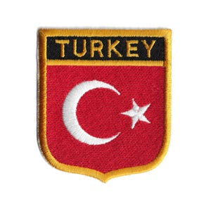 Könnte beinhalten: Gestickter Aufnäher mit der türkischen Flagge, einem roten Hintergrund mit einem weißen Halbmond und Stern, und dem Wort "TURKEY" in gelben Buchstaben auf schwarzem Hintergrund.