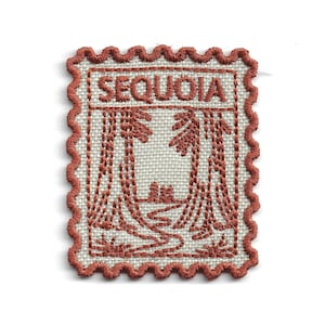 May include: A rectangular embroidered patch with a scalloped edge in rust-colored thread on a cream-colored fabric base. The design features a forest scene with two large trees and a winding path, with the word SEQUOIA stitched in rust at the top.