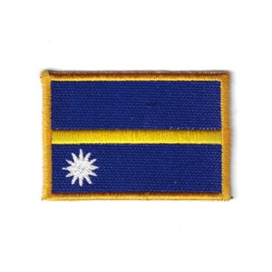 Pode incluir: Um patch retangular com a bandeira de Nauru. O design inclui um fundo azul, uma faixa horizontal amarela e uma estrela branca no canto inferior esquerdo. O patch tem uma borda dourada.