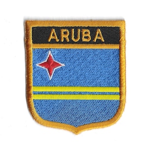 May include: Embroidered patch featuring the word "ARUBA" in gold lettering on a black background. The patch has a blue field with a red star and yellow stripe, framed by a gold border. The patch is shield-shaped.