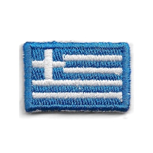 May include: A rectangular embroidered patch featuring the flag of Greece. The design consists of alternating horizontal blue and white stripes with a white cross centred on a blue square in the upper left corner, all finished with a blue border.