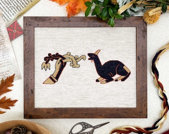 May include: A framed cross-stitch embroidery depicting a hand holding a stylized branch and a black animal with a long neck and tail. The embroidery is on a beige linen fabric and the frame is dark brown wood.