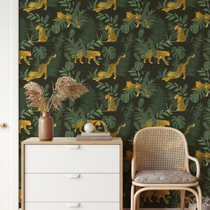 May include: A dark green wallpaper with a repeating pattern of yellow leopards and green leaves. The wallpaper is in a room with a white dresser and a wicker chair.